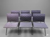 four chairs with woven seats are arranged in a row on a gray surface