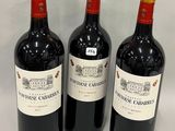 three bottles of red wine are lined up on a white surface
