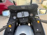 a close up of a motorcycle dashboard with a car in the background