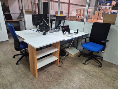 a desk with two computers and a chair in a room