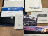 Plusieurs brochures Mercedes sont posées sur une table, à côté d'un portefeuille