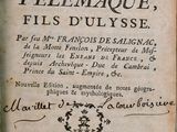 un vieux livre posé sur une table en bois, à côté d'une plante