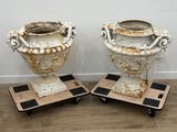 une paire d'urnes anciennes en fonte, posées sur des pieds en fonte, sur un sol en bois