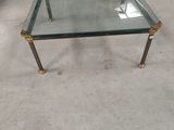 a glass coffee table with brass legs and a glass top