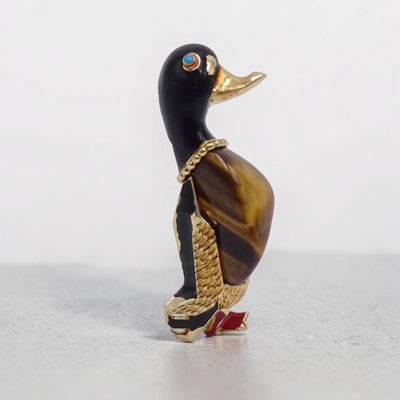 une figurine de canard noire et dorée posée sur une surface blanche
