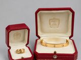 two red leather jewelry boxes with gold rings inside of them