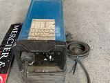 a blue welding machine sitting on the ground next to a sign