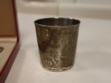 a silver cup sitting on a table next to a box