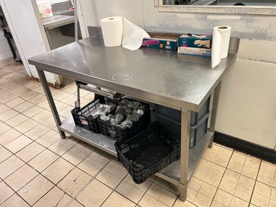 une table en acier inoxydable sur laquelle sont posés deux rouleaux de papier toilette