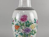un vase avec des fleurs peintes dessus, posé sur une table