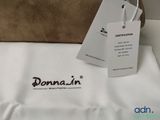 a brown bag with a tag on it sitting on a bed