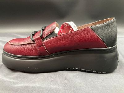 le mocassin rouge et noir repose sur une surface grise