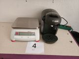 a coffee maker and a scale sitting on a counter