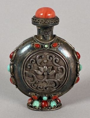 silver flask with red and green beads on a stand