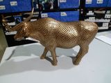 une statue de vache en or posée sur une table blanche dans un magasin