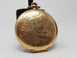 a gold colored pocket watch with a bird on it