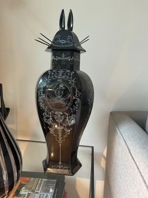 a black vase sitting on a glass table next to a book