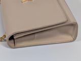 the small beige purse is sitting on the table with a chain around it