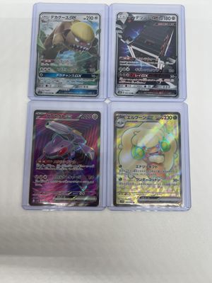 four different pokemon cards in plastic cases on a white surface
