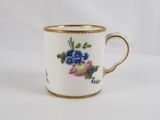 a close up of a cup with flowers on it on a white surface