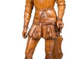 wooden statue of a man holding a dog on a wooden base
