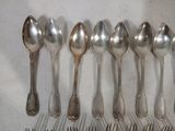 six cuillères en argent sont alignées sur une surface blanche