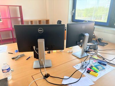 deux écrans d'ordinateur posés sur un bureau, avec un clavier et une souris