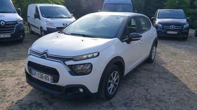 une petite voiture blanche garée sur un parking avec d'autres voitures