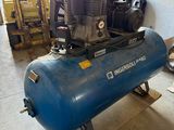 a blue air compressor sitting on a cart in a garage