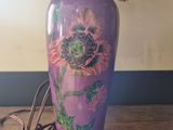 a purple vase with a flower painted on it on a table