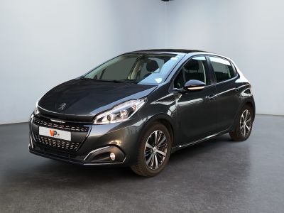 La voiture grise est garée dans une grande pièce où se trouve une horloge accrochée au mur.