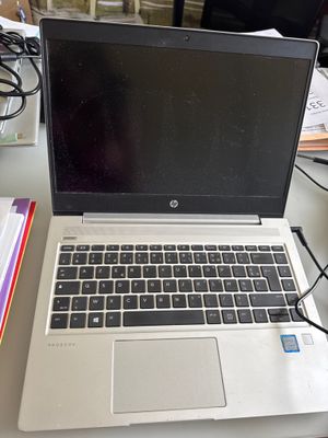 un ordinateur portable posé sur un bureau, à côté d'une pile de papiers