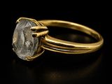 a close up of a gold ring with a diamond on a black surface