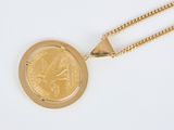 a close up of a gold coin with a chain on a white surface