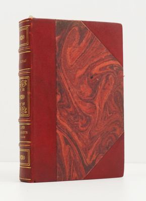 un vieux livre à la couverture rouge posé sur une surface blanche