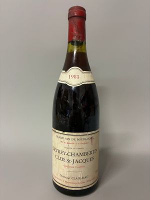 bottle of red wine with a red cap sitting on a white surface