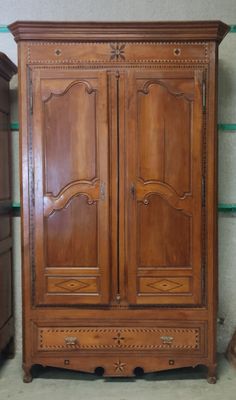 a wooden armoire in a room with a green shelf