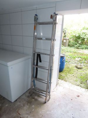 une échelle appuyée contre le mur, à côté d'un lave-linge et d'un sèche-linge