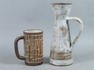 un pichet blanc et une chope marron posés l'un à côté de l'autre