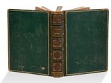 un livre vert ouvert sur une surface blanche