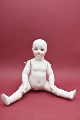 une petite poupée blanche assise par terre sur un fond rouge