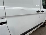 the side of a white van parked in a parking lot next to a building