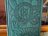 an old book sitting on top of a green chair next to a bookshelf