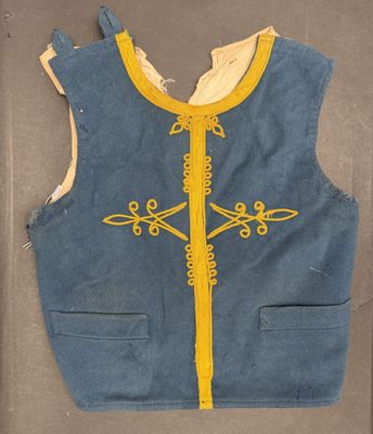 un vieux gilet bleu avec des bordures jaunes et une croix sur le devant