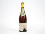 une vieille bouteille de vin posée sur une surface blanche
