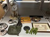 a table with various items on it that include a clock, a figurine, and other items