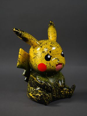 figurine de pikachu jaune et noir assise sur une surface grise