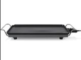 a close up of a grill on a white surface with a black handle