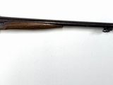 un fusil accroché au mur dans une pièce avec un fond blanc