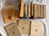 Plusieurs livres sont posés sur un lit recouvert d'un drap blanc.